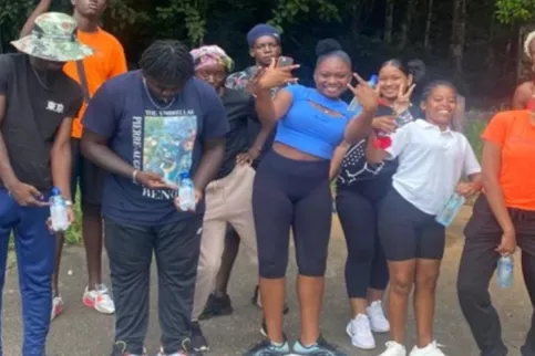 Jeunes de 16 à 29 ans qui sont debout et sourient, font des mouvements de joie dans un espace ouvert avec des arbres en arrière fond